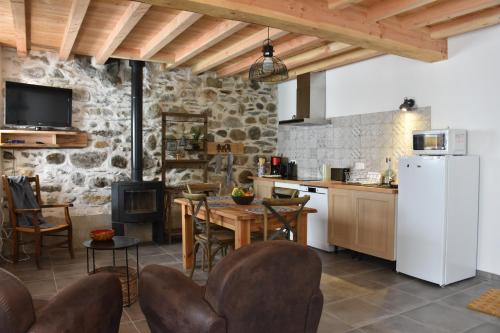 a kitchen with a white refrigerator and a table and chairs at Gite du Carbounet et la Grange de Lou in Siguer