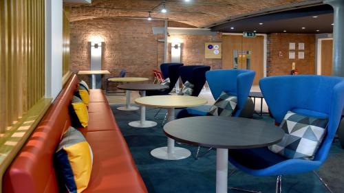 a waiting room with tables and blue chairs at Holiday Inn Express Liverpool-Albert Dock, an IHG Hotel in Liverpool