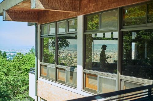 a house with large windows with a man in the reflection at ANDO HOTEL NARA Wakakusayama -DLIGHT LIFE & HOTELS- in Nara