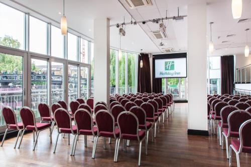 a conference room with red chairs and a screen at Holiday Inn London Camden Lock by IHG in London