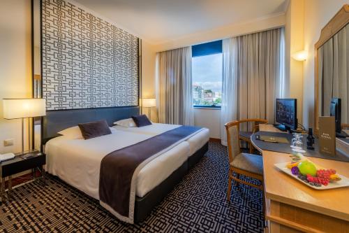a hotel room with a bed and a desk with a computer at Hotel Mundial in Lisbon