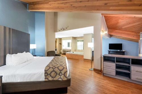 a hotel room with a bed and a television at Baymont by Wyndham Tupelo in Tupelo