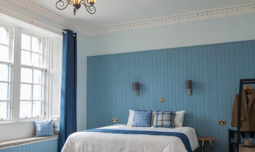 a bedroom with a blue wall and blue curtains at Coorie in Dunfermline