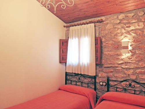 a bedroom with two beds and a stone wall at Casa El Ros II - Turistrat in Vall dʼAlba