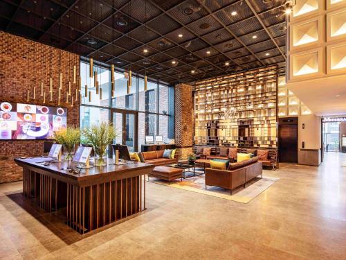 a lobby with couches and tables in a building at Mercure Ambassador Seoul Hongdae in Seoul