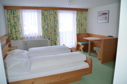 1 dormitorio con 2 camas, escritorio y ventana en Pension Kirchbrugger, en Telfes im Stubai