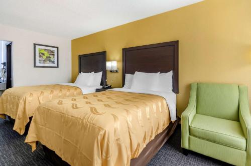 a hotel room with two beds and a green chair at Quality Inn Verona - Staunton North in Staunton