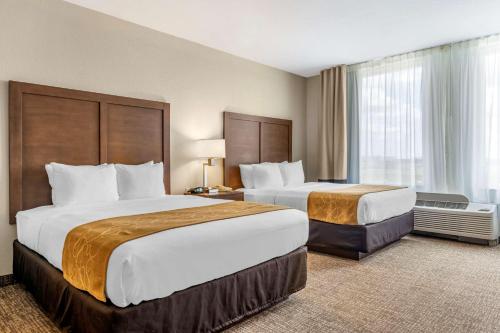 a hotel room with two beds and a window at Comfort Suites Maingate East in Orlando
