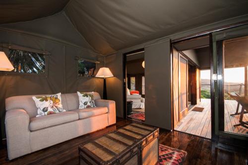 ein Wohnzimmer mit einem Sofa und einem Tisch in der Unterkunft HillsNek Safari Camp – Amakhala Game Reserve in Amakhala Game Reserve