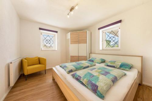 a bedroom with a bed and a yellow chair at Ferienwohnung Mayenburg-schlosshof in Vollan