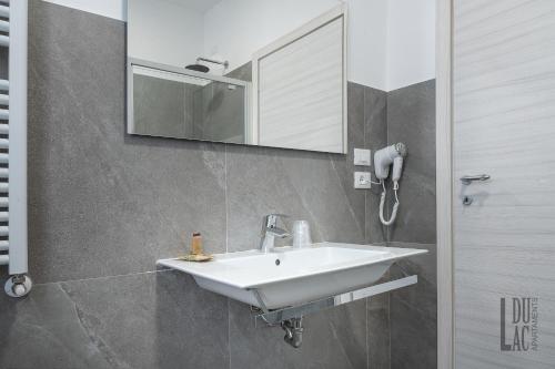 y baño con lavabo blanco y espejo. en Du Lac Aparments en Desenzano del Garda