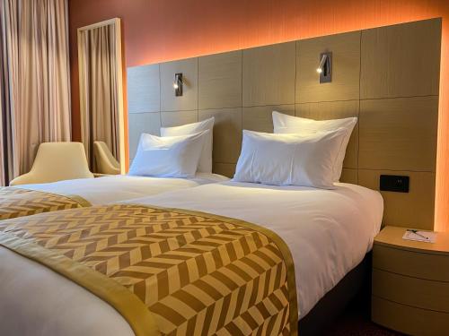a hotel room with two beds with white pillows at Nash Airport Hotel in Geneva