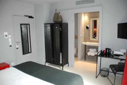 a bedroom with a black cabinet and a bathroom at Hotel Pont Levis - Franck Putelat in Carcassonne