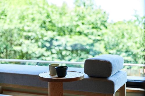 a table with two coffee cups and a chair in front of a window at ANDO HOTEL NARA Wakakusayama -DLIGHT LIFE & HOTELS- in Nara