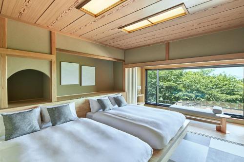 a bedroom with two beds and a large window at ANDO HOTEL NARA Wakakusayama -DLIGHT LIFE & HOTELS- in Nara