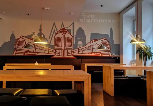 ein Restaurant mit Tischen und Stühlen und einem Wandbild in der Unterkunft Five Elements Hostel Leipzig in Leipzig