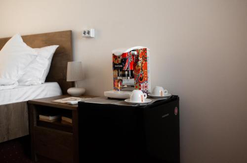 a room with a bed and a night stand with a table with two mugs at Viking Apartment Grigo in Cluj-Napoca