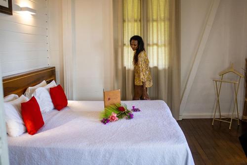 a woman standing next to a bed with flowers on it at Jardin Malanga in Basse-Terre