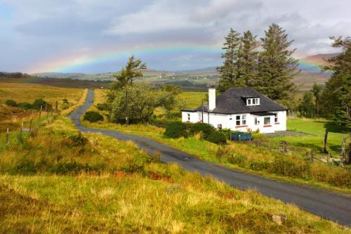 a house on a hill next to a road at The Red Red Robin Cottage in Portree