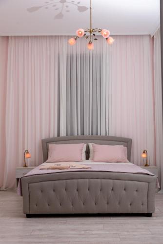 a bedroom with a bed with pink sheets and a chandelier at Theasis Athens in Athens