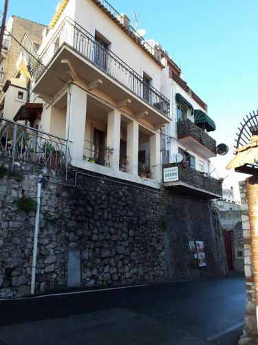 un grande edificio bianco con un muro di pietra di appartamento odeon a Taormina