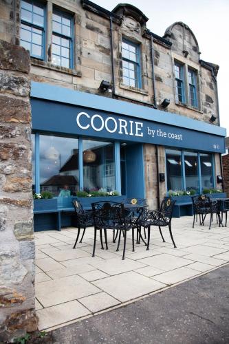 eine Gruppe von Tischen und Stühlen vor einem Geschäft in der Unterkunft Coorie in Dunfermline