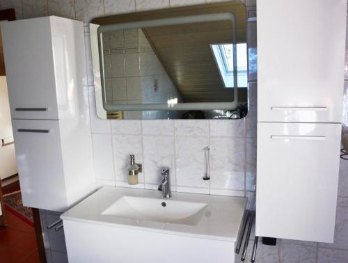 a white bathroom with a sink and a mirror at Ferienwohnung Auszeit Waxweiler in Waxweiler