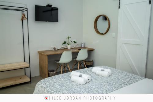 
a bedroom with a bed and a table at Raw Karoo Guest House in Oudtshoorn
