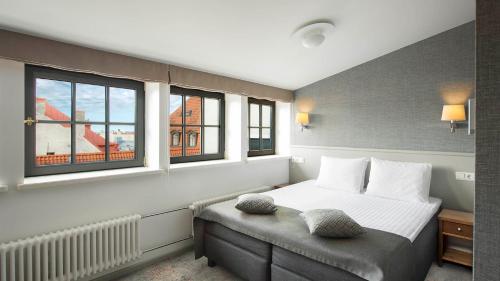 a bedroom with a bed and two windows at Hestia Hotel Barons Old Town in Tallinn