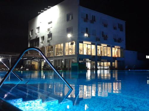 a swimming pool in front of a building at night at Flamingo Resort in Belgrade