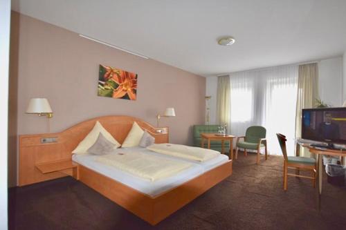 a hotel room with a bed and a television at Landhotel Hauer in Pleisweiler-Oberhofen