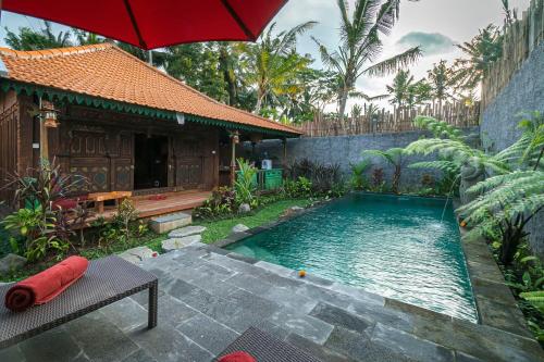 a pool in front of a house with a red umbrella at The Forest Villa Ubud in Ubud