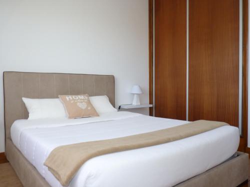 a bedroom with a large white bed with a brown pillow at Home for Travellers ll in Ponta Delgada