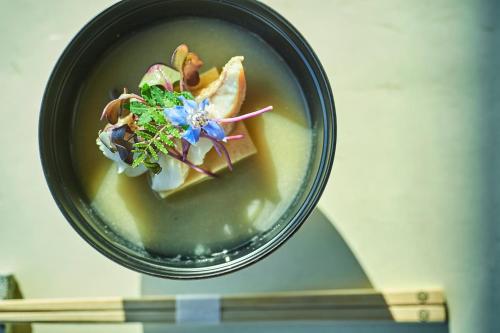 a bowl of soup with a blue flower in it at ANDO HOTEL NARA Wakakusayama -DLIGHT LIFE & HOTELS- in Nara