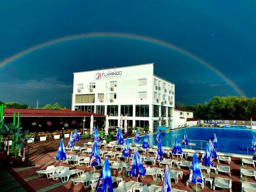 a rainbow over a hotel with a pool with chairs and umbrellas at Flamingo Resort in Belgrade
