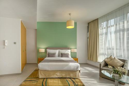 um quarto com uma cama grande e uma cadeira em Grand Heights Hotel Apartments em Dubai