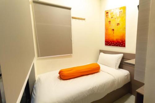 an orange pillow sitting on top of a bed at Front One Residence Syariah Mampang in Jakarta