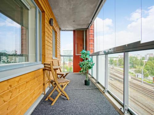 a balcony with two chairs and a plant at Kotimaailma Apartments Oulu in Oulu