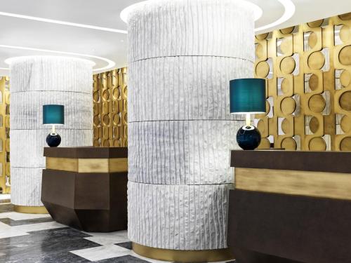 a lobby with two columns with lamps on them at Athens Capital Center Hotel - MGallery Collection in Athens