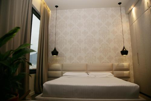 a white bed in a room with a window at La Bohème Hotel in Tirana