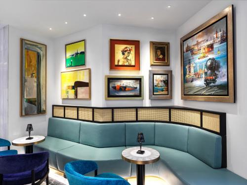 a waiting room with a blue couch and chairs at Athens Capital Center Hotel - MGallery Collection in Athens