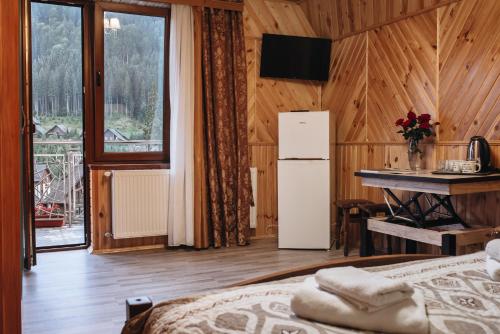 a bedroom with a refrigerator and a table and a desk at Sadyba u Halyny in Bukovel