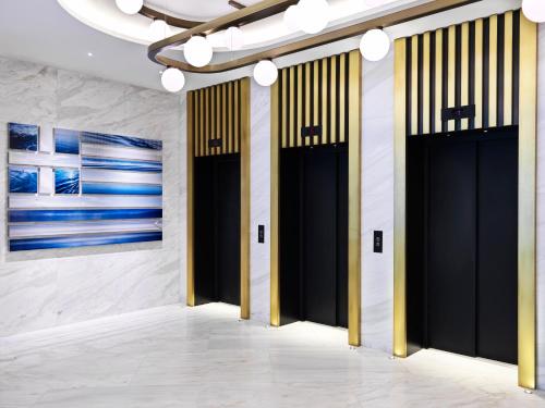 a hallway with black doors and paintings on the walls at Athens Capital Center Hotel - MGallery Collection in Athens