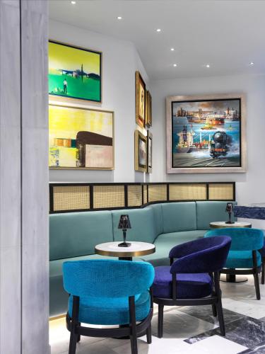 a waiting room with a green couch and blue chairs at Athens Capital Center Hotel - MGallery Collection in Athens