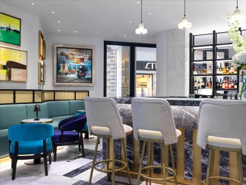 a bar with blue and white chairs in a restaurant at Athens Capital Center Hotel - MGallery Collection in Athens