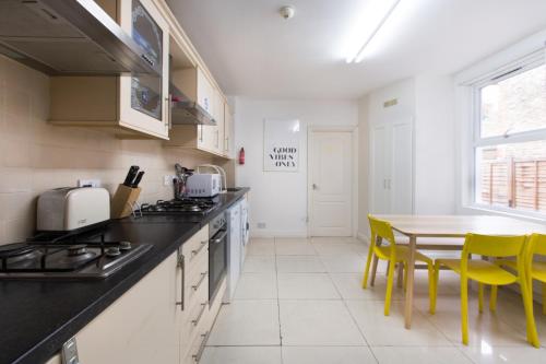 a kitchen with a table and yellow chairs at Tooting Broadway Studios & Rooms by PrimeCityHosts in London