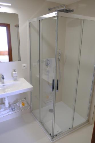 a shower with a glass door next to a sink at Hotel Continental in Brno