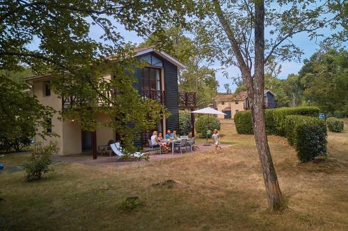 a family sitting at a table outside of a house at Résidence Château de Salles in Salles