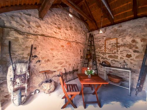 Habitación con mesa y sillas en una pared de piedra. en Wild Boar Cottage - Romantic getaway en Badacsonytomaj