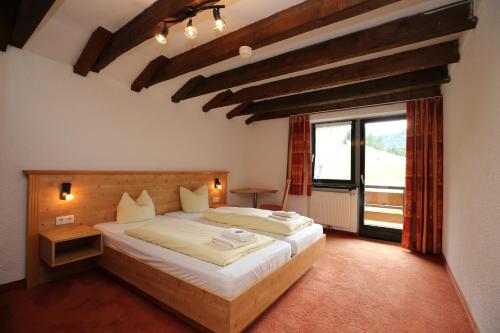 a bedroom with a bed and a large window at T3 Alpenhotel Garfrescha in Sankt Gallenkirch